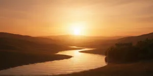 Serene sunrise over a rolling landscape with a winding river in the middle.